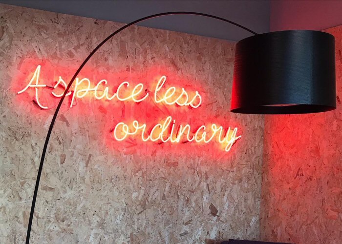 A space less ordinary' orange neon sign. Real glass neon fitted directly onto the wall.