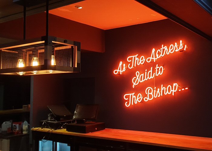 As The Actress, Said to The Bishop…' amber neon sign. Real glass neon fitted directly onto wall.