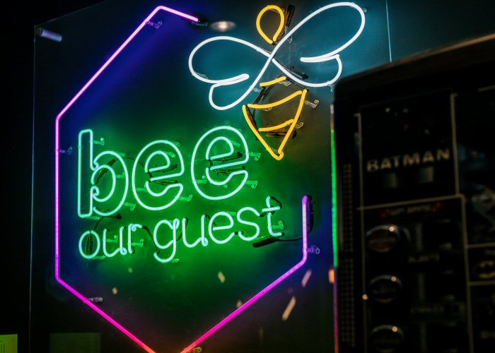 bee our guest' multi-coloured neon sign. Real glass neon fitted directly on the wall with clear acrylic cover.