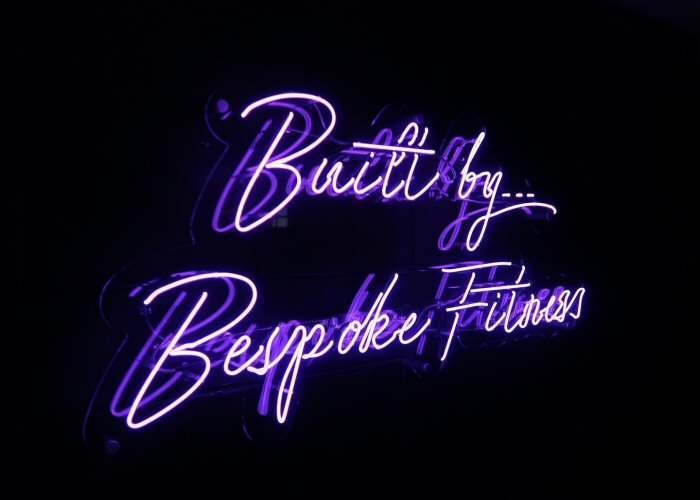 Built by Bespoke Fitness' purple neon sign. Real glass neon on a clear acrylic panel cut to shape.