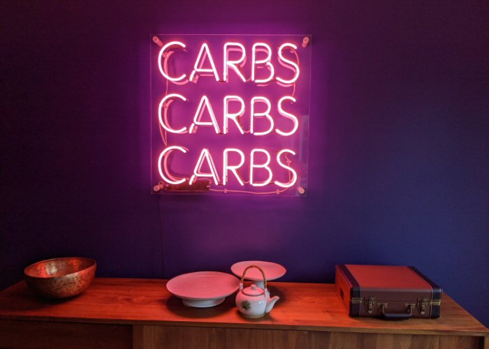 CARBS CARBS CARBS' pink neon sign. Real glass neon mounted on clear acrylic panel.