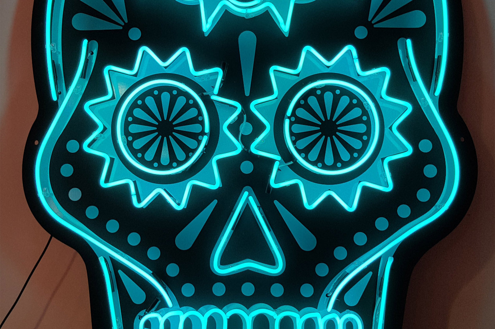 Changos skull' turquoise neon sign. Real glass neon mounted onto black acrylic panel cut to shape.