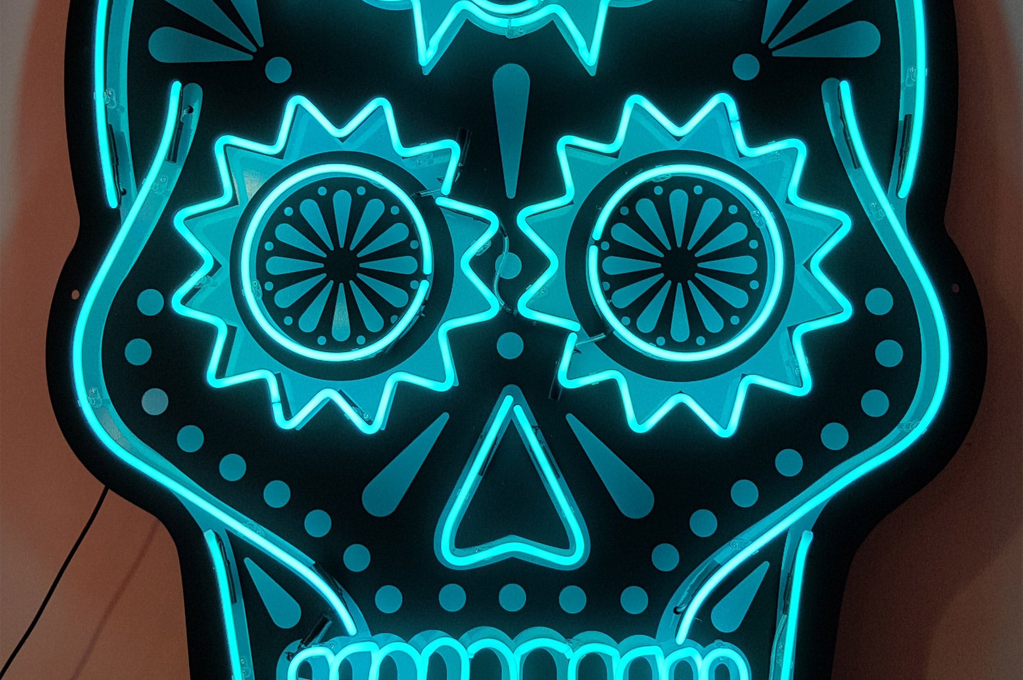 Changos skull' turquoise neon sign. Real glass neon mounted onto black acrylic panel cut to shape.