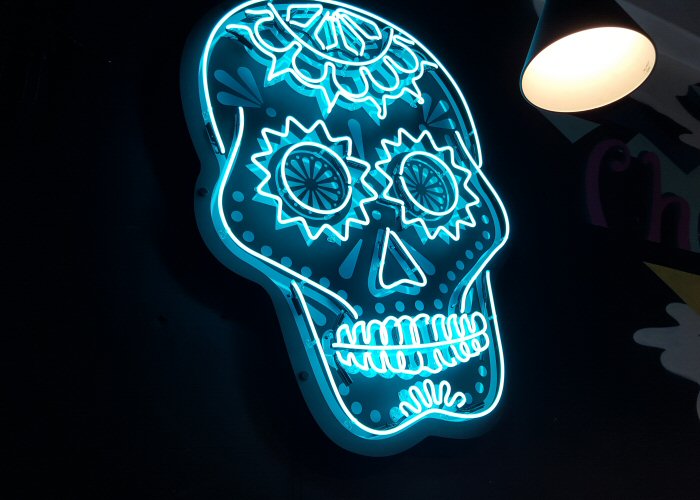 Changos skull' turquoise neon sign. Real glass neon mounted onto black acrylic panel cut to shape.