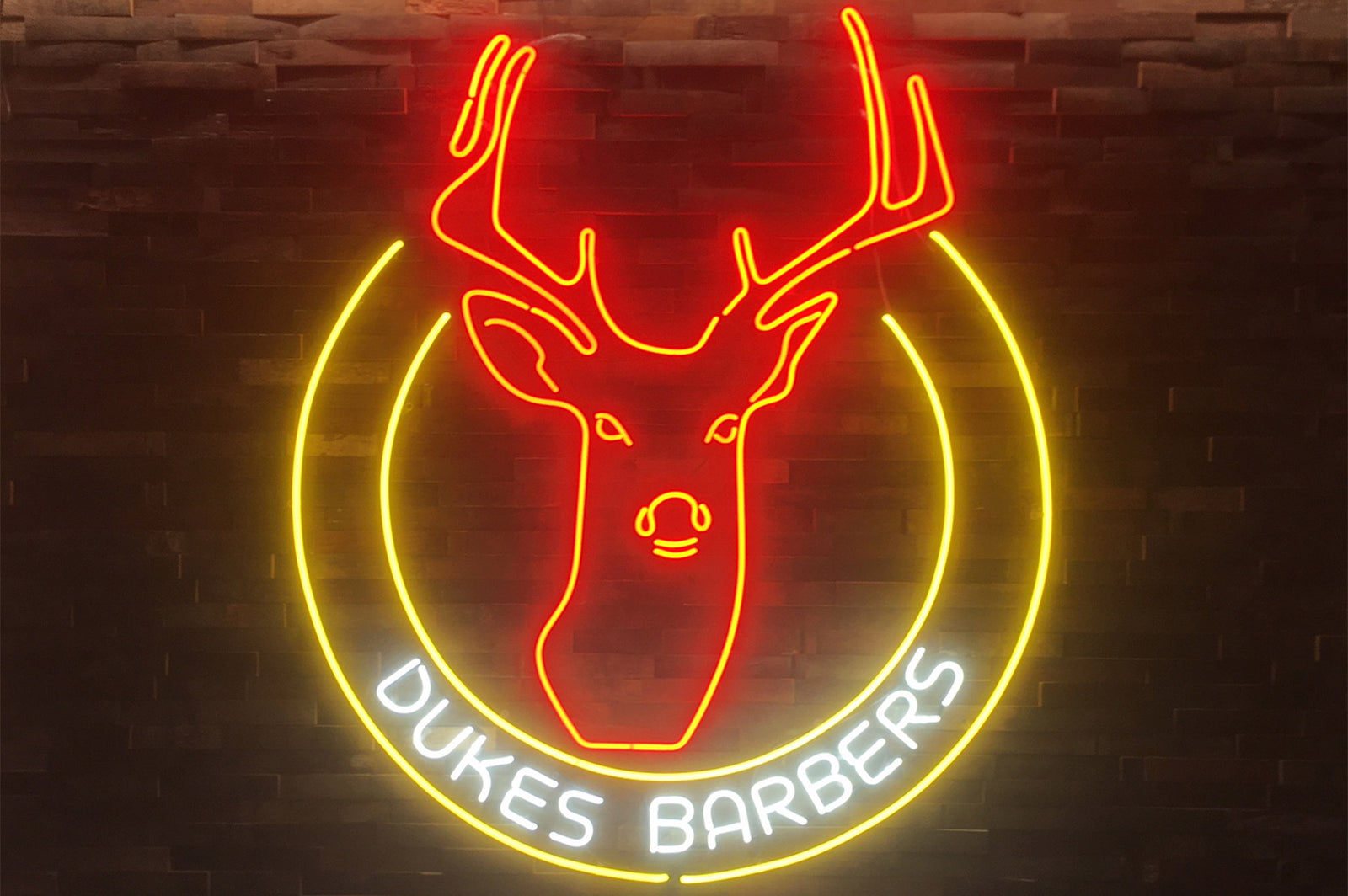 Dukes Barbers logo' orange, yellow and white neon sign. Real glass neon fitted directly onto the wall.