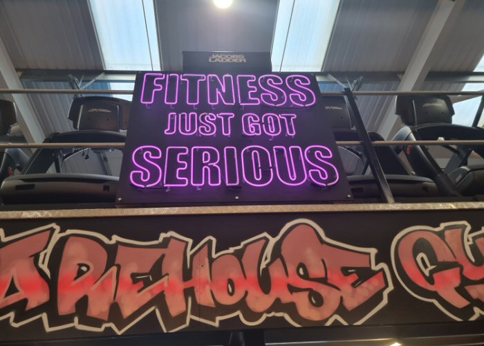 FITNESS JUST GOT SERIOUS' purple neon sign. Real glass neon fitted onto a black acrylic panel.