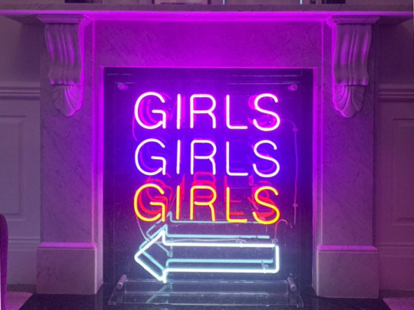 GIRLS GIRLS GIRLS' neon sign for home. Real glass neon on a free standing clear acrylic panel.