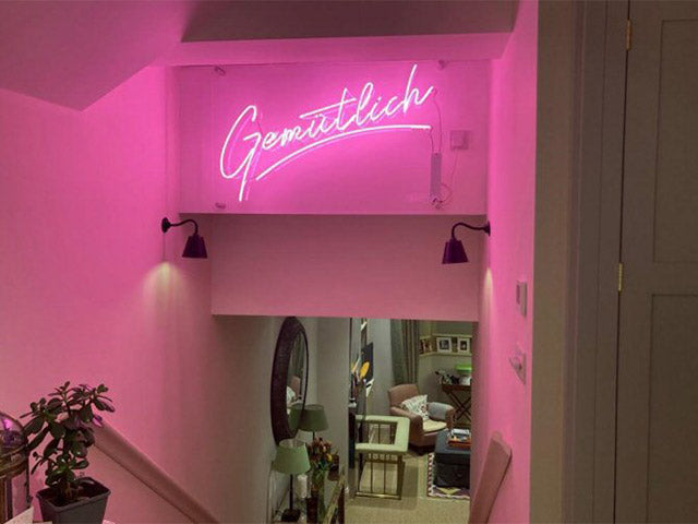 Gemutlich' pink neon sign. Real glass neon mounted on clear acrylic panel.