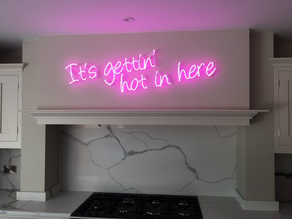 It's gettin' hot in here' pink neon sign. Real glass neon fitted directly onto wall.