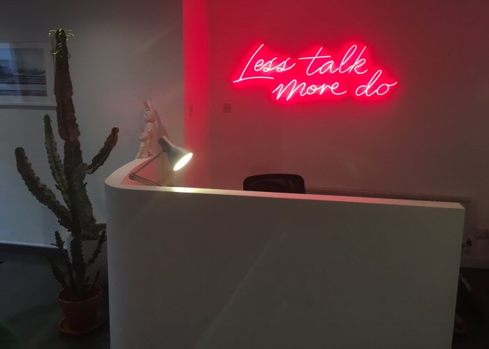 Less talk more do' pink neon sign. Real glass neon fitted directly onto the wall.