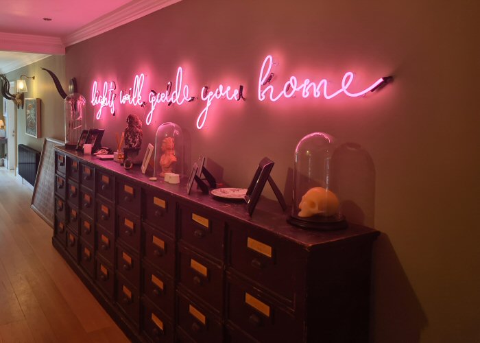 lights will guide you home' pink neon sign. Real glass neon mounted directly onto wall.