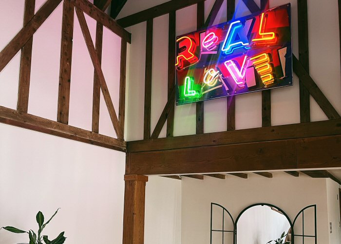 Real Love' multi-coloured neon sign. Real glass neon mounted on to old signage board.