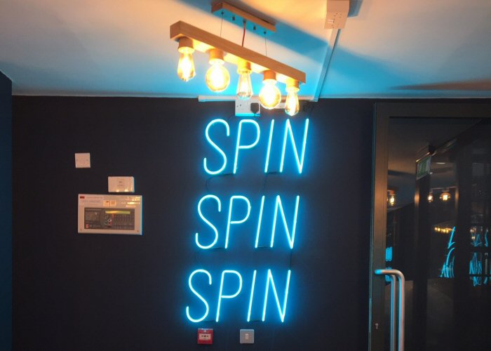 SPIN SPIN SPIN' turquoise neon sign. Real glass neon fitted directly onto the wall.