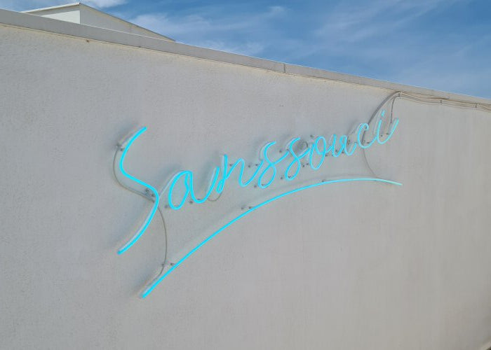 Sanssouci' turquoise neon sign. Real glass neon fitted directly onto wall.