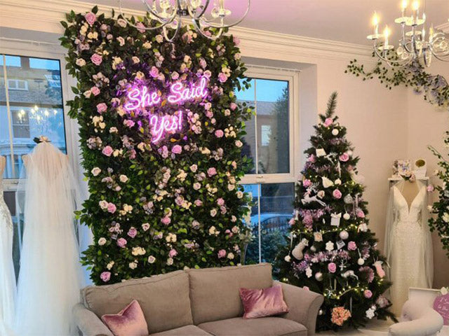 She Said Yes!' pink neon sign. Real glass neon fitted onto flower wall.