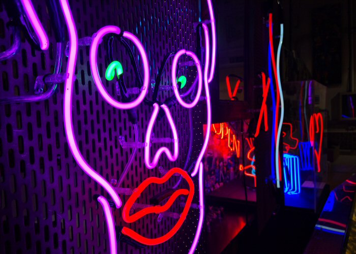 Lippy Skull' purple and red neon artwork. Real glass neon mounted onto perforated metal sheet.