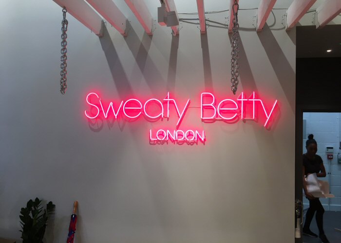 Sweaty Betty' pink neon sign. Real glass neon fitted directly onto the wall.