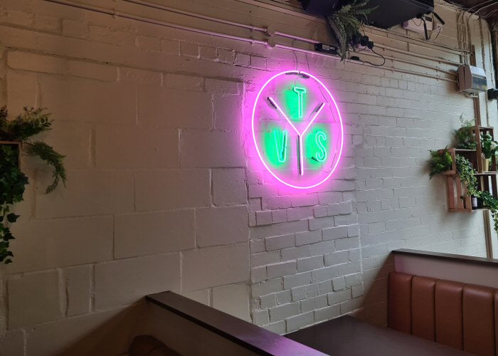 TVS logo' green and pink neon sign. Real glass neon fitted directly onto wall.
