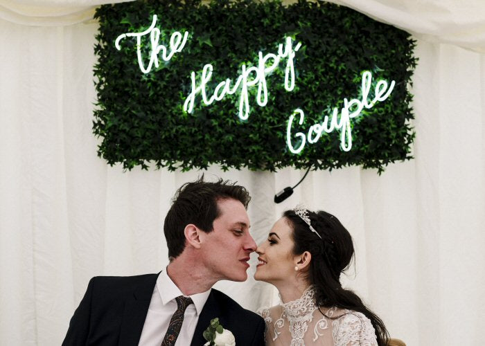 The Happy Couple' white neon sign. Real glass neon fitted onto artificial foliage panel.