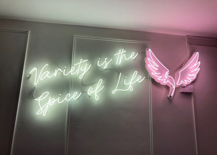 Variety is the Spice of Life' white and pink neon sign. Real glass neon fitted directly onto wall and white panel cut to shape.