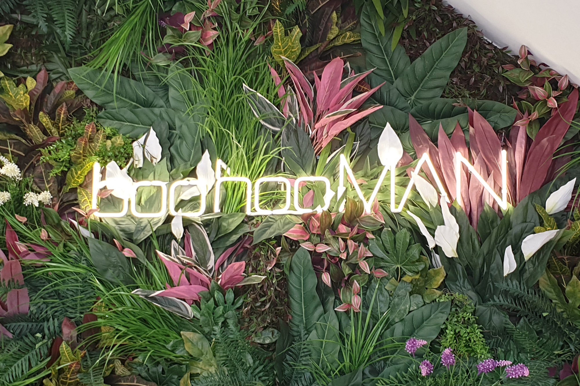 boohooMAN' white neon sign. Real glass neon fitted onto artificial foliage.