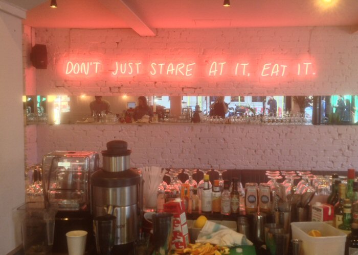 DON'T JUST STARE AT IT, EAT IT' pink neon sign. Real glass neon fitted directly onto wall.