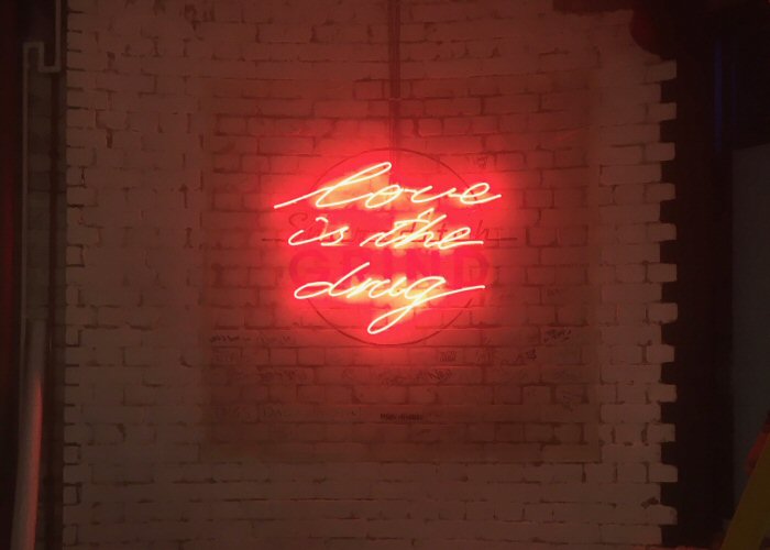love is the drug' red neon art. Real glass neon fitted directly onto the wall.