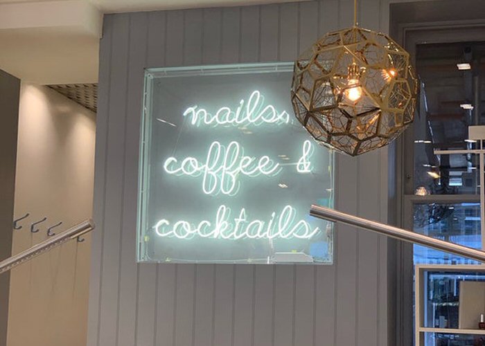 nails, coffe & cocktails' white neon sign. Real glass neon fitted inside clear acrylic case.