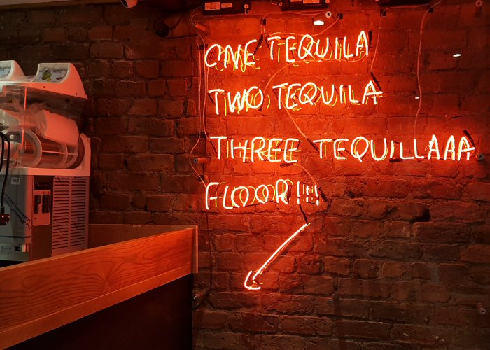 one tequila two tequila' red neon sign. Real glass neon fitted directly on the wall with clear acrylic cover.
