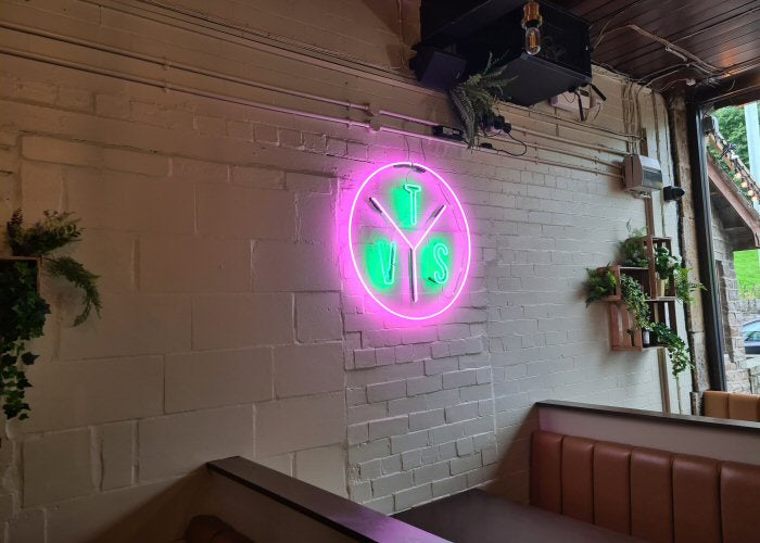 TVS logo' green and pink neon sign. Real glass neon fitted directly onto wall.